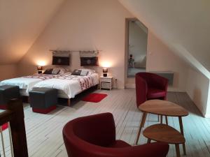 een slaapkamer met een bed en 2 stoelen bij Villa du Cerf Thibault in Le Blanc