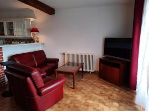 a living room with a couch and a flat screen tv at Villa du Cerf Thibault in Le Blanc