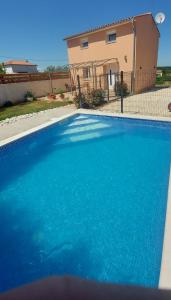 a large blue swimming pool in front of a house at Holiday home Silva in Peruški