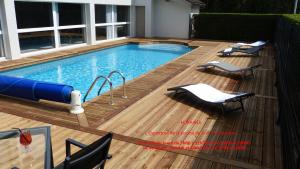 einen Pool auf einer Holzterrasse mit Stühlen und einem Pool in der Unterkunft Hotel ARBOR - Les Hunaudieres - Le Mans Sud - Mulsanne in Mulsanne
