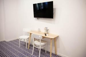 een tafel met twee stoelen en een televisie aan de muur bij White Blu House - Massa Lubrense Sorrento in Massa Lubrense