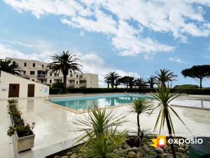 duży basen z palmami i budynkami w obiekcie Studio 4 couchages piscine , plage , vue canigou w mieście Saint-Cyprien