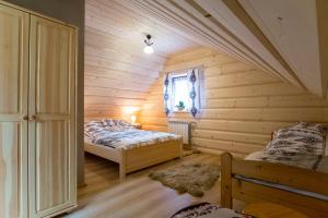 two beds in a room with wooden walls at Apartamenty u Gabi in Poronin +91 photos