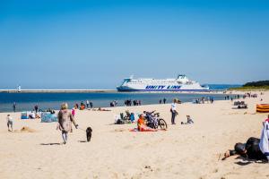 a group of people on a beach with a cruise ship at Apartament z widokiem - visitopl in Świnoujście
