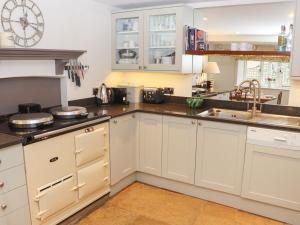 una cocina con armarios blancos y fregadero en Manor Cottage en Cirencester
