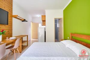 a bedroom with a bed and a desk and a green wall at Estúdios 3 Praias in Ubatuba +28 photos