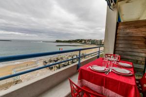 a table on a balcony with a view of the beach at Studio la Pergola in Saint-Jean-de-Luz