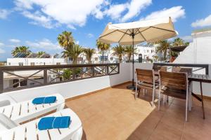 einen Balkon mit einem Tisch, Stühlen und einem Sonnenschirm in der Unterkunft Holiday in Lanzarote! in Tías