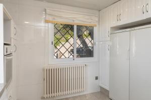 cocina blanca con ventana y radiador en Hauzify I Casa Suredes, en Fanals d'Aro