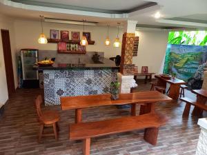une salle à manger avec des bancs en bois et un bar dans l'établissement D'JERO HomeStay, à Ubud