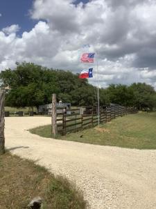 dos banderas en una cerca al lado de un camino de tierra en Constantino Farms Campsites Tent Camping, en Wilson