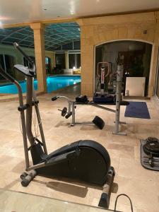 a fitness room with a gym with a swimming pool at Villa & Spa dans le Périgord in Proissans
