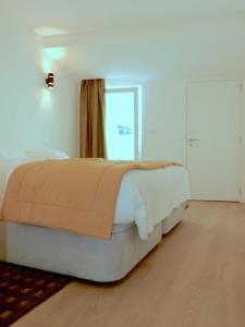 a white bedroom with a bed with a window at Consuls Ocean View in Ponta Delgada