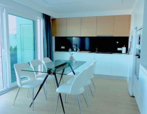 a kitchen with a glass table and white chairs at Consuls Ocean View in Ponta Delgada
