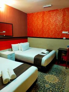 two beds in a hotel room with red walls at HOTEL SRI IMPIAN in Johor Bahru