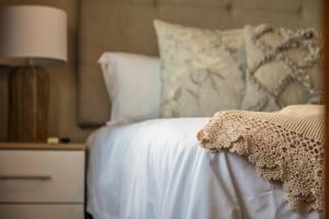 a bed with white sheets and pillows and a lamp at Beacon Wharf , George Hay 6 Seafront Accommodation in Mossel Bay