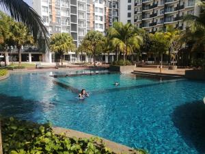 a woman swimming in a swimming pool with palm trees at Timurbay Seafront Residence in Kuantan