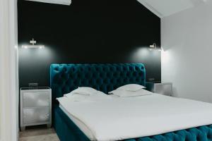 a bedroom with a large bed with a blue velvet headboard at Fullton Central in Cluj-Napoca