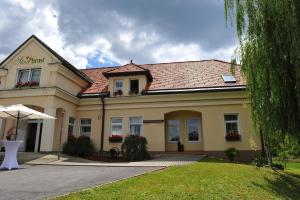 un grande edificio giallo con un ombrello davanti di Gostišče - Guest house STARI HRAST a Ljutomer