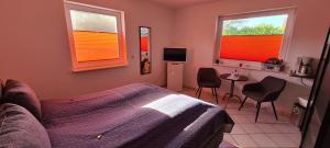ein Schlafzimmer mit einem Bett und einem Tisch und zwei Fenstern in der Unterkunft Erholung Pur bei Familie Peters in Fehmarn