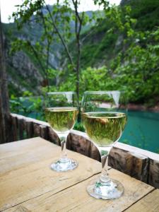due bicchieri di vino bianco seduti su un tavolo di legno di Riverside Komani Lake a Koman