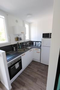 cocina blanca con fregadero y nevera en Studio tout confort - Climatisation, parking, wifi, en Gréoux-les-Bains