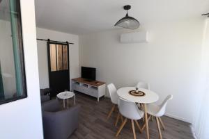 ein Wohnzimmer mit einem Tisch und weißen Stühlen in der Unterkunft Studio tout confort - Climatisation, parking, wifi in Gréoux-les-Bains