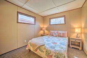 a small bedroom with a bed and two windows at Cozy Petoskey Area Retreat on Burt Lake Access! 