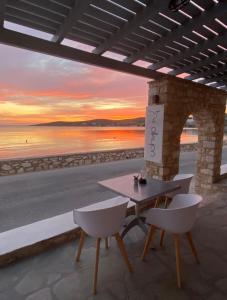 a table and chairs on a patio with a sunset at Alkyon Hotel in Parikia