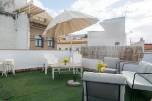 un patio con una mesa y una sombrilla en el techo en ESSE Apartamentos Las Setas, en Sevilla