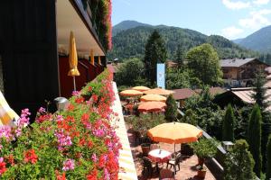 a balcony with tables and umbrellas and flowers at Hotel Sonnleiten in Reit im Winkl