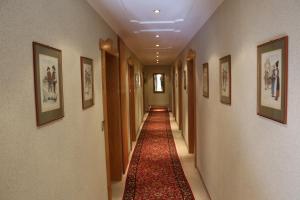 a long hallway with a red carpet and pictures on the walls at Hotel Sonnleiten in Reit im Winkl