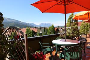 a patio with a table and chairs and an umbrella at Hotel Sonnleiten in Reit im Winkl
