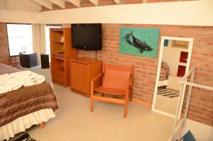1 dormitorio con 1 cama y TV en la pared en Las Anémonas Sur en Puerto Madryn
