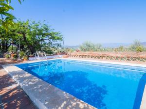 a swimming pool with blue water and trees in the background at Cubo's Casa Rural La Guillena in Alhaurín el Grande