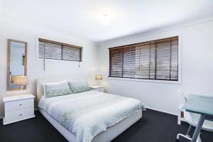 a white bedroom with a bed and a desk at Private Room in Pleasant Ashmore in Gold Coast