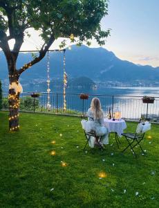 a woman sitting at a table in the grass at Il Bellavista in Lezzeno