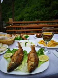 a table with plates of food and a glass of wine at Riverside Komani Lake in Koman