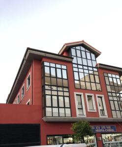 un gran edificio rojo con grandes ventanas en Apartamentos Verdemar (VUT), en Llanes