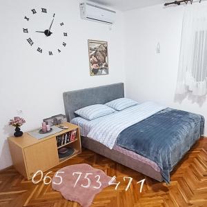 een slaapkamer met een bed en een klok aan de muur bij Apartman CITRUS Trebinje in Trebinje