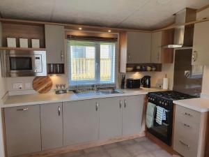 a kitchen with white cabinets and a stove top oven at Beautiful Borders Cabin in Jedburgh