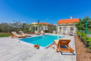 a swimming pool with two lounge chairs and a house at Holiday house Olive Tree in Kaočine