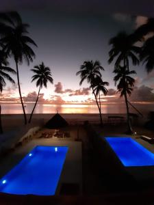 een resort met 2 zwembaden en palmbomen bij zonsondergang bij Coco Rise Villas - by Hostly in Bwejuu