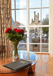 a glass table with a vase with red roses on it at Royal Athenaeum Suites in Aberdeen