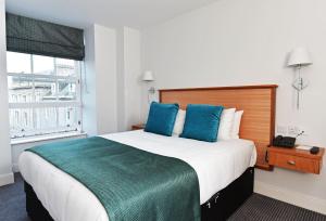 a hotel room with a large bed with blue pillows at Royal Athenaeum Suites in Aberdeen