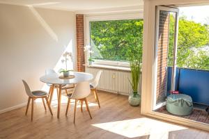 une salle à manger avec une table et des chaises et une fenêtre dans l'établissement Moin Apartment Mit 2 Balkonen u kostenlosen Parkmöglichkeiten, à Bremerhaven