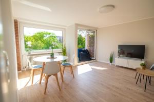 un salon avec une table, des chaises et une télévision dans l'établissement Moin Apartment Mit 2 Balkonen u kostenlosen Parkmöglichkeiten, à Bremerhaven