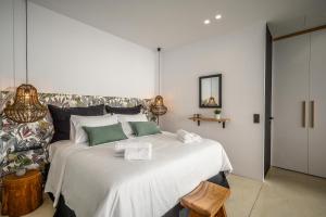 a bedroom with a large white bed with green pillows at Talise I Luxury Suites in Stalida