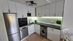 a kitchen with white cabinets and a stainless steel refrigerator at Casa Soñada - Dream House in Garrucha