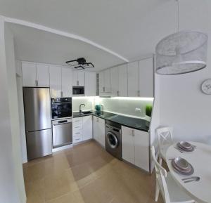 a kitchen with white cabinets and a stainless steel refrigerator at Casa Soñada - Dream House in Garrucha